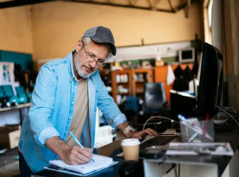 Small business owner reviewing paperwork and managing daily operations at a computer.