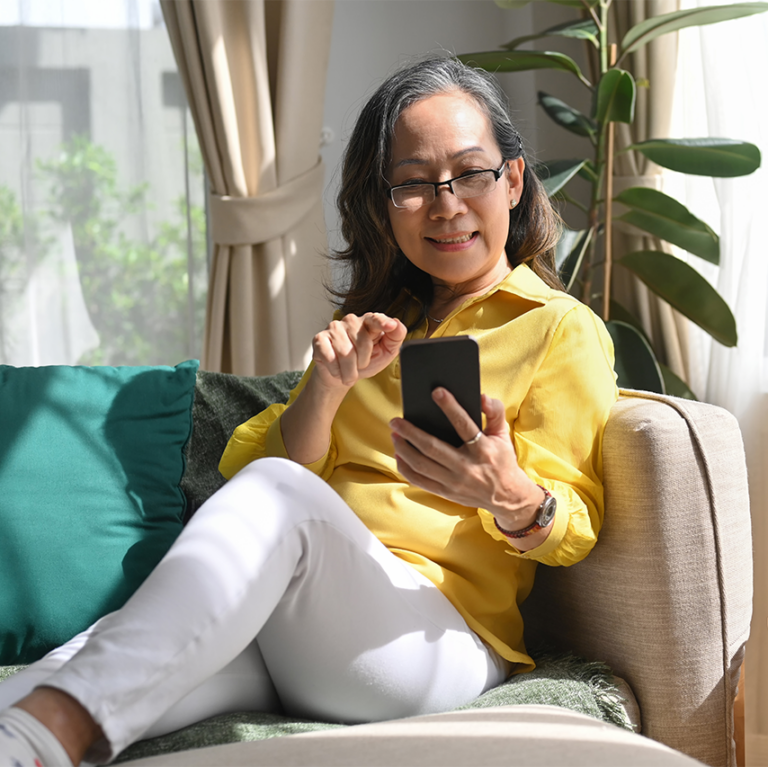 Older woman sitting on a couch using a smartphone image