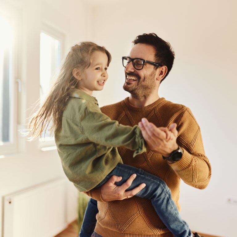 Happy father having fun while dancing with his small daughter after moving into a new apartment.