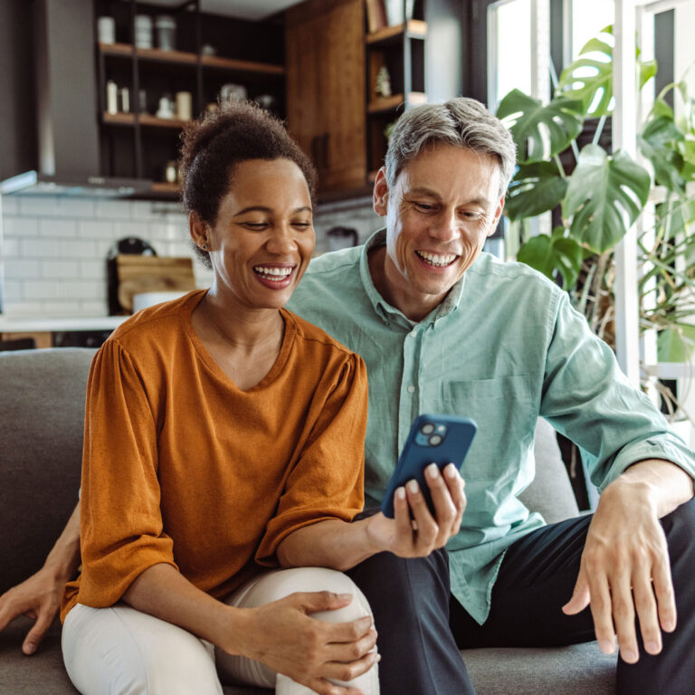 Couple sitting on couch looking at cell phone