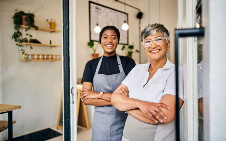 small business owners standing outside of business smiling