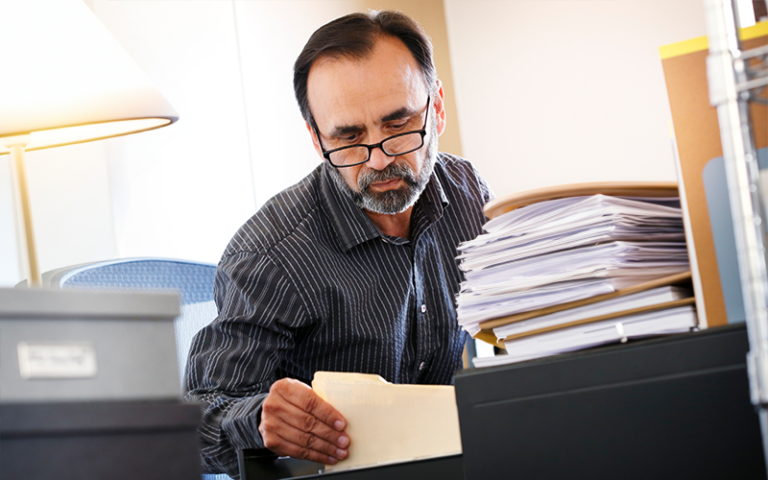 Man looking through filing cabinet for documents needed to file divorce.