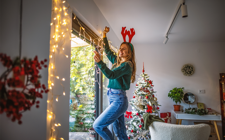 Young woman happily decorating her home for Christmas.