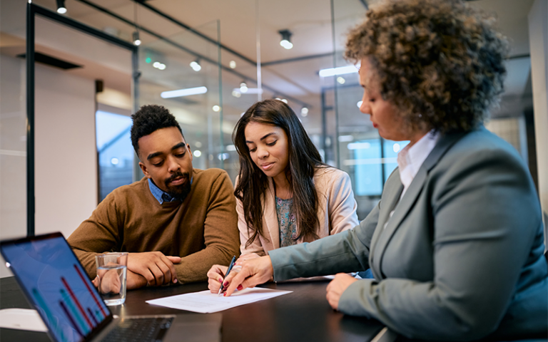 A couple sits down with a banker to talk about home refinance options.