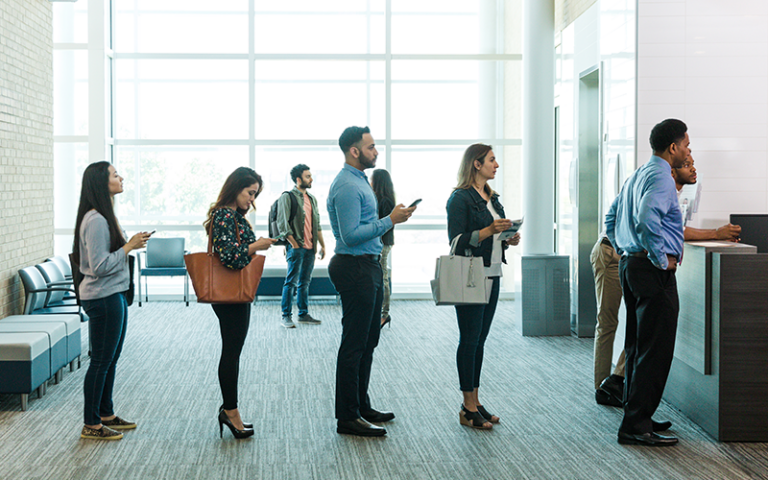 Small business customers waiting in line at a bank, representing the importance of secure check handling to prevent fraud.