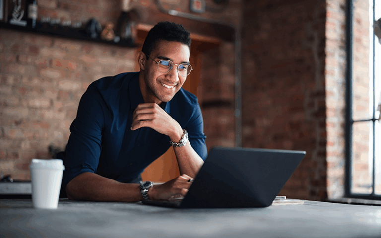 Man standing at kitchen counter looking at his laptop.